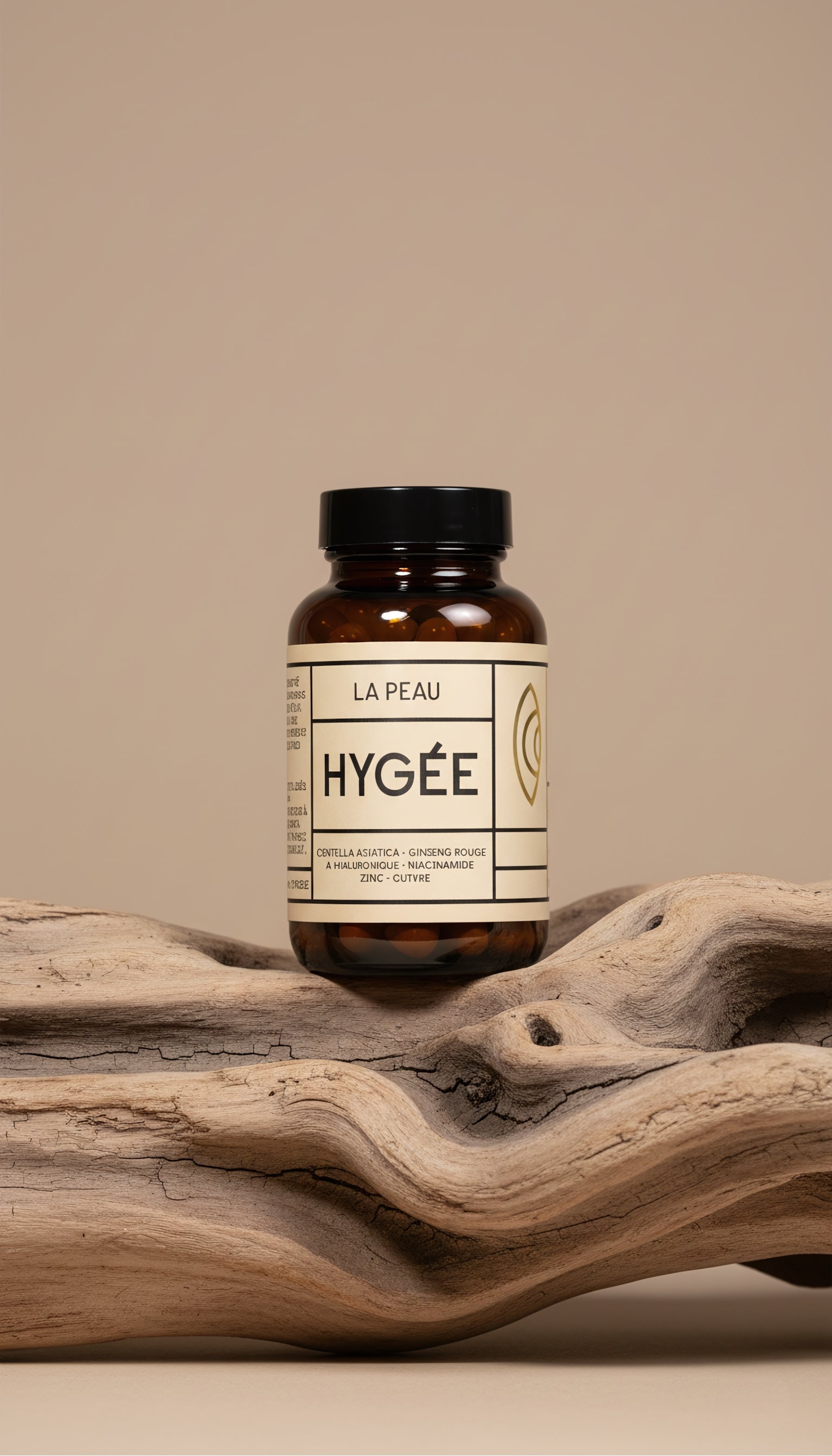 Amber HYGÉE La Peau skin supplement jar with cream label and black lid balanced on a curved piece of driftwood against a soft beige studio backdrop.